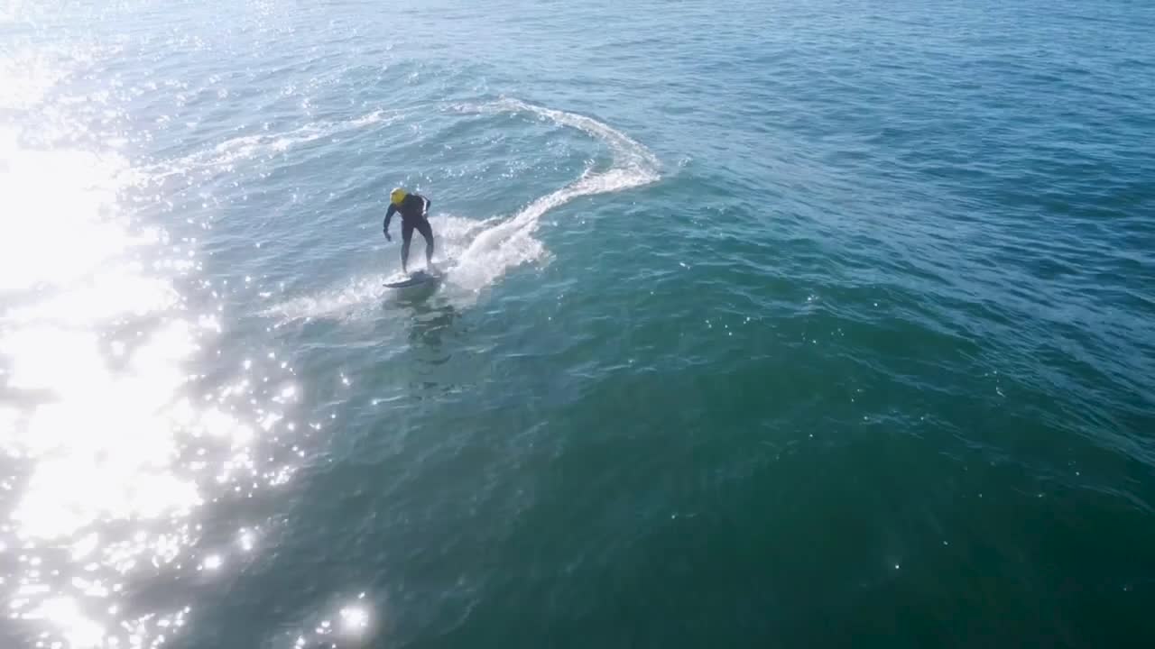 Young surfer catching and riding a good wave on a sunny day with blue water.