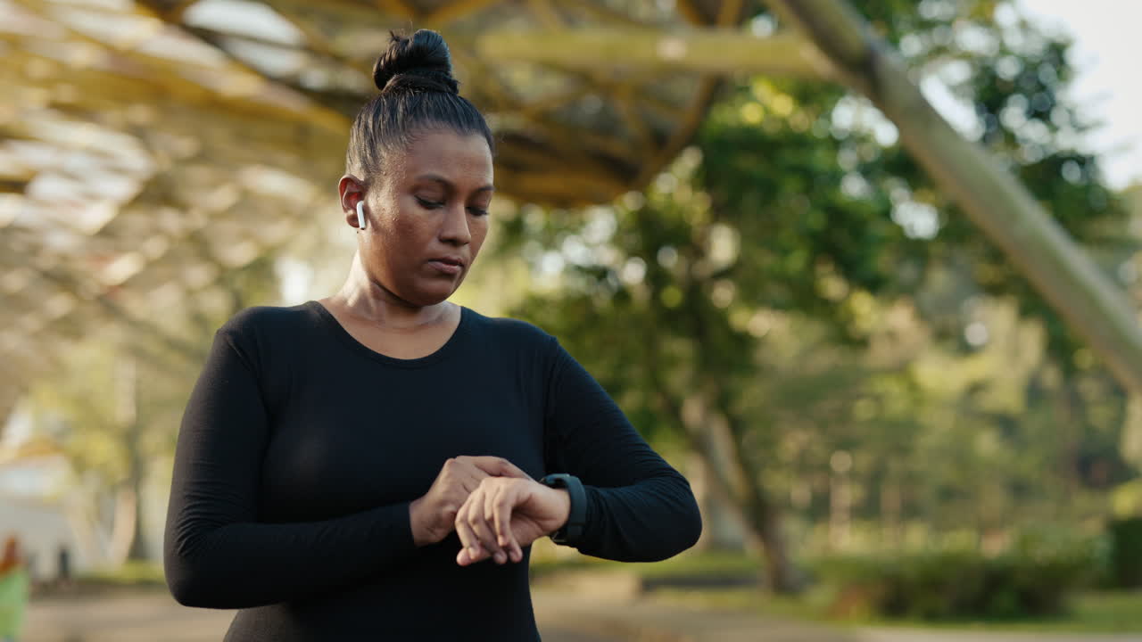 Woman checks her smartwatch while exercising outdoors