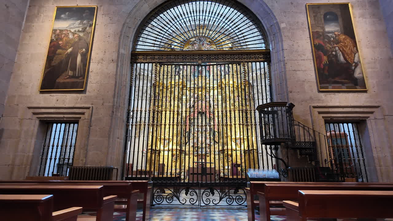 Fast approach inside cathedral showing symmetrical altar, benches and ornate gate with religious atmosphere in Spain
