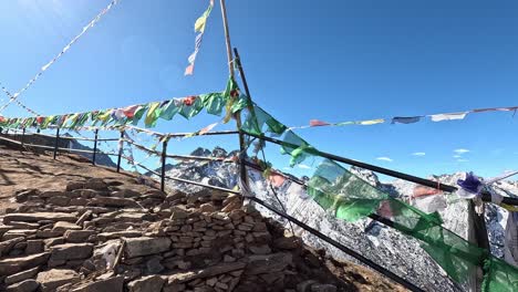 looking over a beautiful snowy mountain chain with fresh snow. revealing behind prayer flags on a railing. high altitudes in . laurebina mountain pass on gosaikunda trek