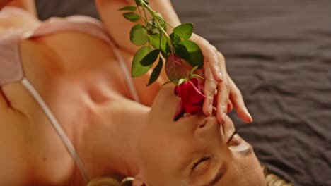 an attractive woman dressed in sexy lingerie enticingly plays with a rose and smiles in joy
