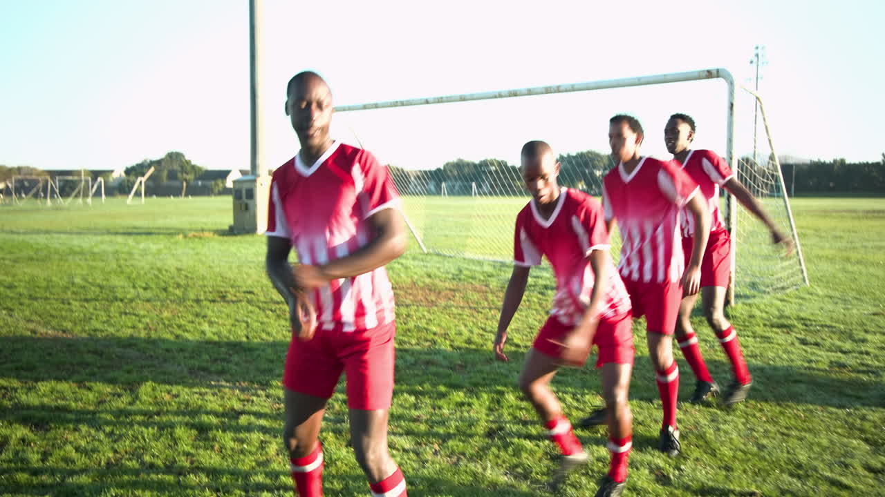 Playing soccer, male team in red uniforms warming up on field