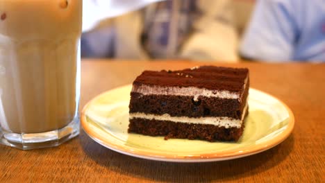 enjoying a slice of tiramisu with iced coffee at a cafe