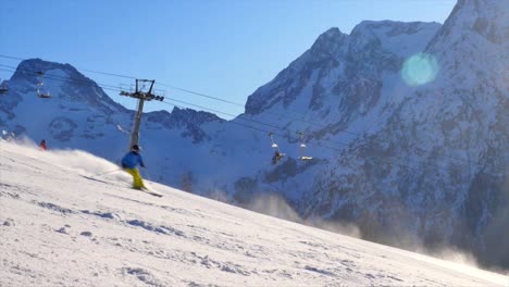 unrecognizable single skier going down a steep black piste praying snow with beautiful mountain background on a sunny day with blue skies