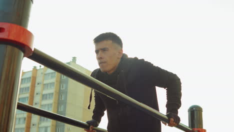 man practicing dips on parallel bars while training outdoor