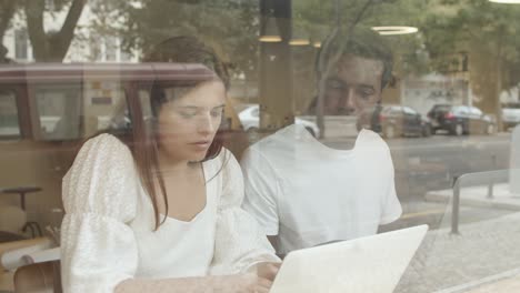 Diverse-young-colleagues-using-laptop-and-talking