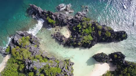 aerial pedestal down on hidden beach and clear shallow waters surrounded by limestone cliffs in el nido, palawan, the philippines