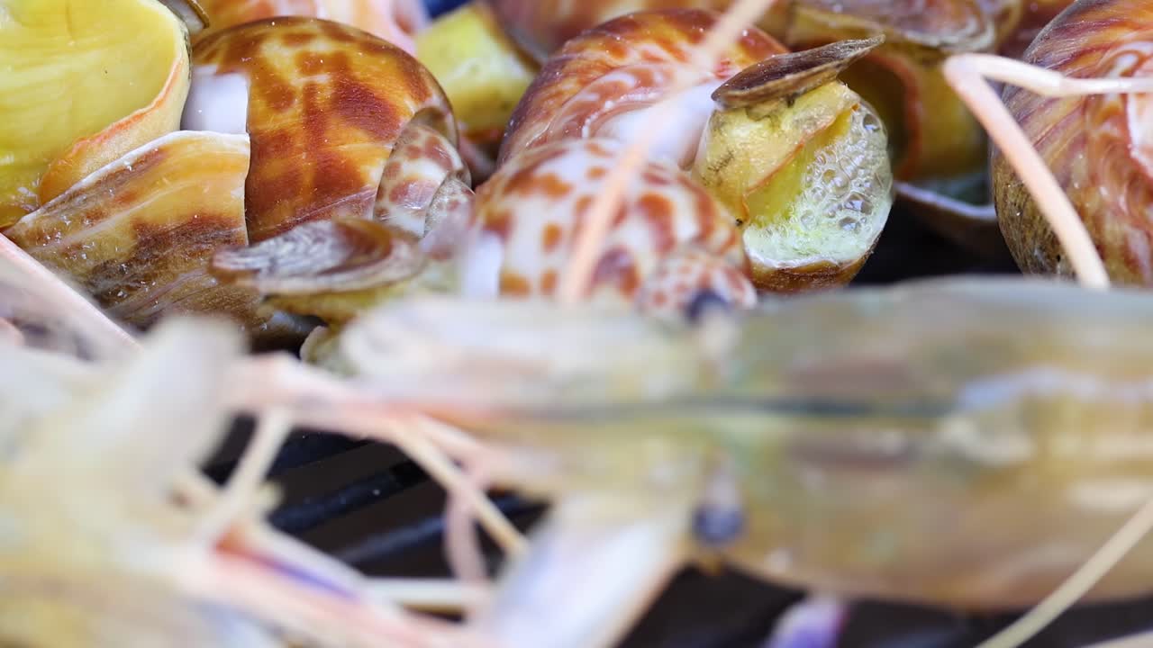 Detailed view of shrimp and snails sizzling on a barbecue grill, showcasing their textures and colors.