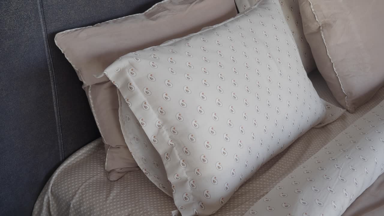 primer plano de una almohada blanca con patrón de paisley en una cama