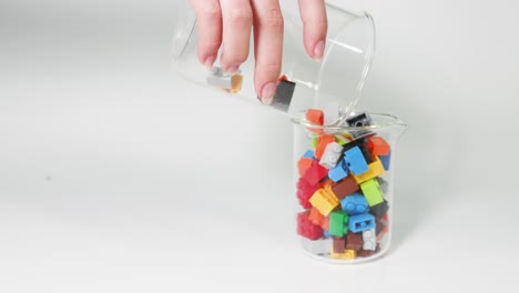 hands moving colorful blocks from one jar to another