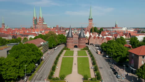 Incline-Hacia-Arriba-Para-Revelar-El-Centro-Histórico-De-La-Ciudad.-Casas-De-Ladrillo-Rojo,-Iglesias-Y-Edificios.-Volar-Entre-Las-Torres-De-La-Puerta-De-Holsten.-Lübeck,-Schleswig-Holstein,-Alemania