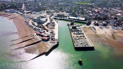 A-dolly-backwards-aerial-view-of-Whitstable-Harbour,-with-a-calm-sea