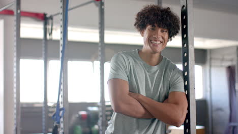 smiling man in gym crossing arms, standing near exercise equipment, copy space