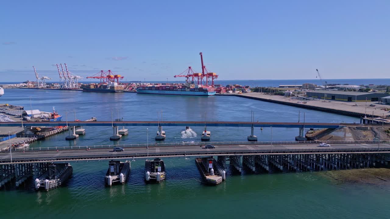 los coches conducen sobre el puente de tráfico de fremantle con buques de carga de contenedores en el fondo, perth, australia occidental