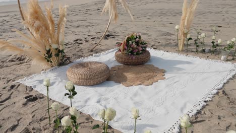 elegant boho picnic arrangement with flowers on a beach blanket at golden hour