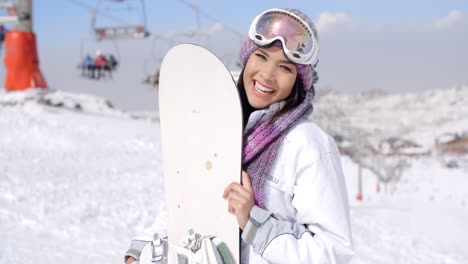 Lachende-Junge-Frau-Mit-Ihrem-Snowboard