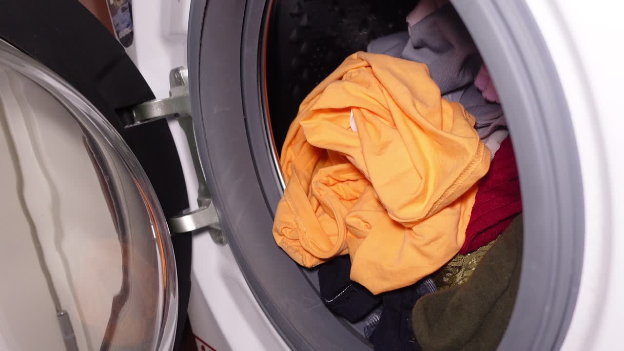 Hand loading clothes into a washing machine