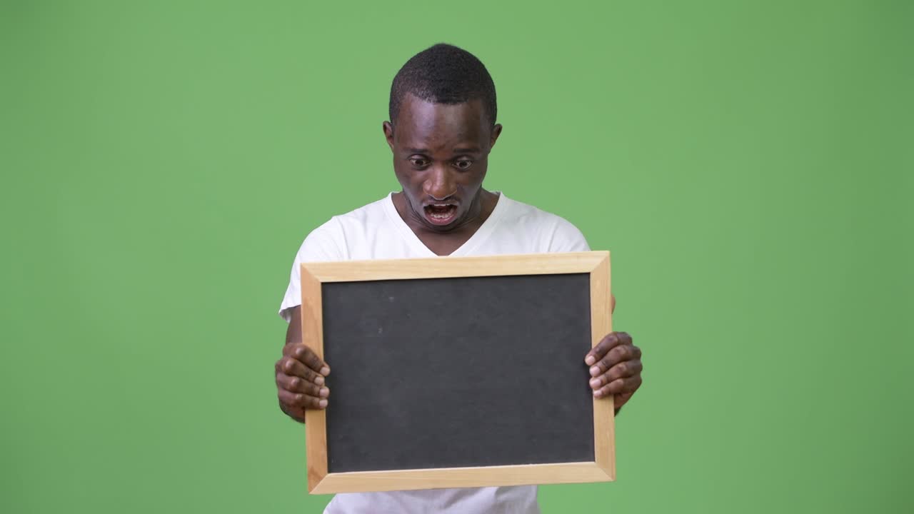 joven africano mostrando la pizarra y mirando conmocionado