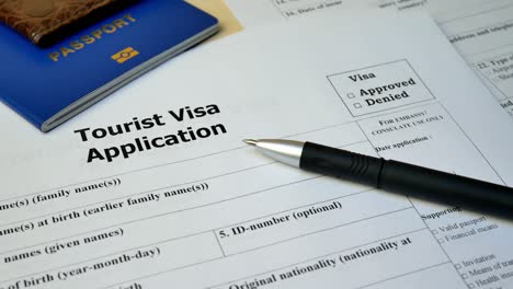 tourist visa application form with passport and pen