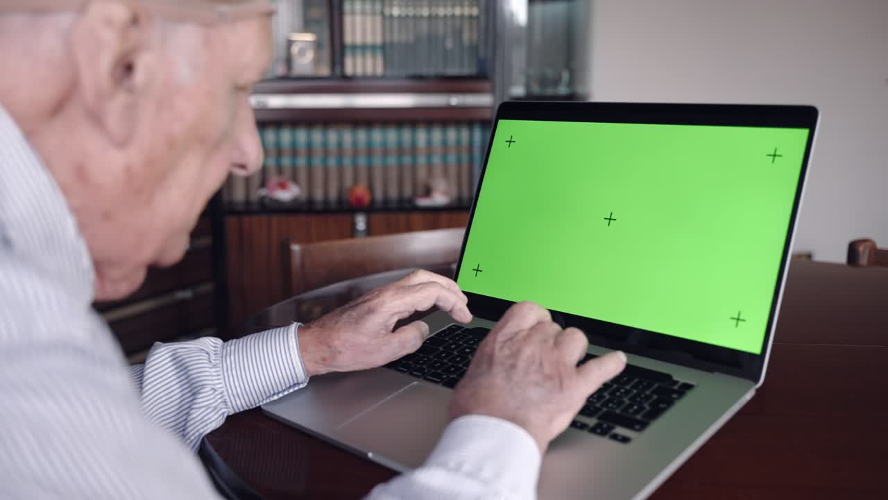 viejo profesor jubilado sentado en la mesa en la sala de estar y trabajando en una computadora portátil de moda, profesor sénior escribiendo en el teclado de la computadora con sus viejas manos arrugadas. profesor en el lugar de trabajo creando proyecto