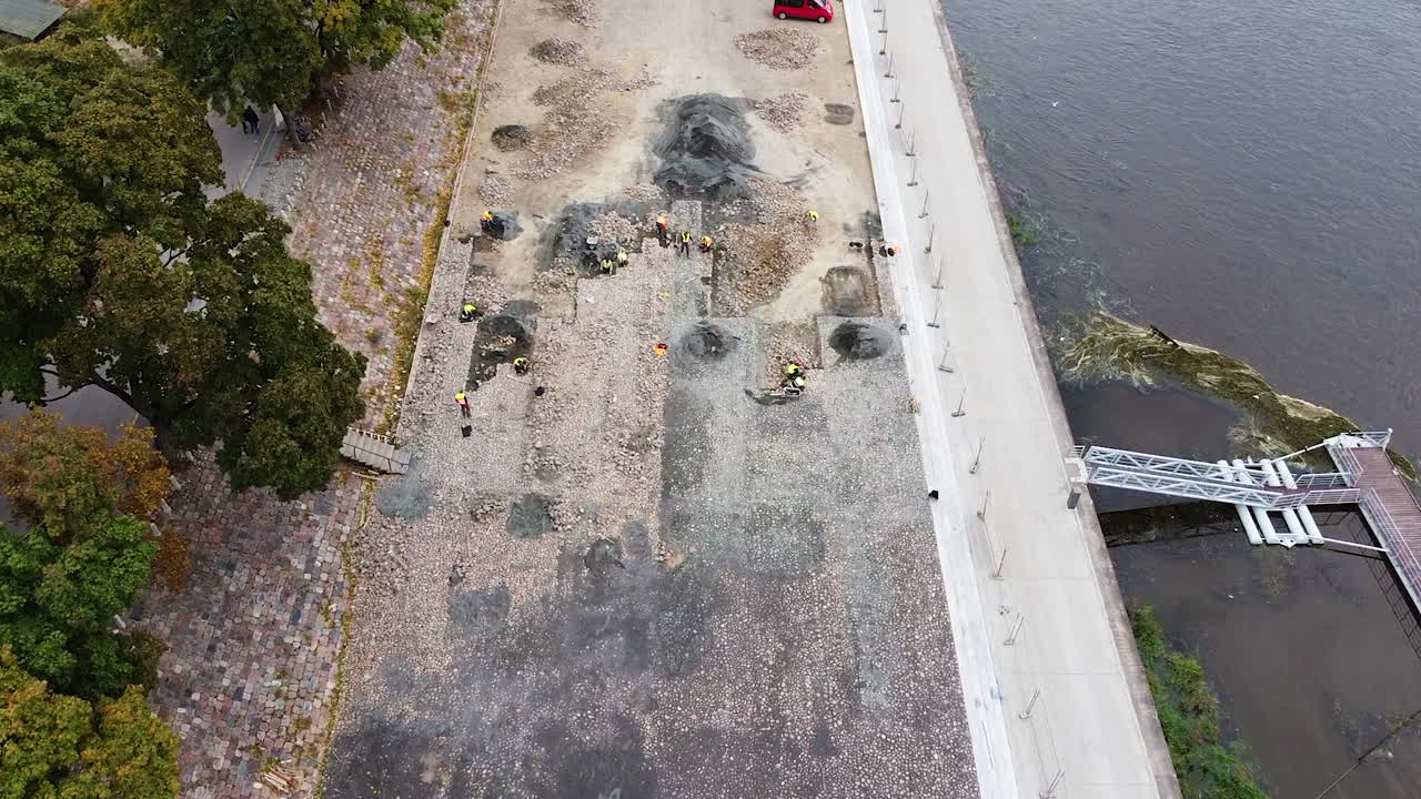 personas que trabajan en excavaciones arqueológicas junto al río, sobrevolando la vista