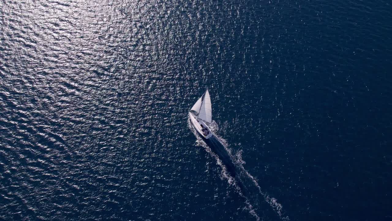 Vista aerea panoramica di una barca a vela che naviga in acque cristalline.