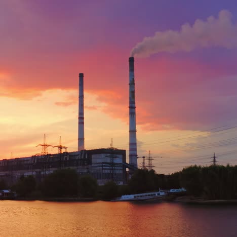 industry against beautiful evening sky. chemical factory and high-voltage electric lines on the riverbank at sunset. pollution of the environment.