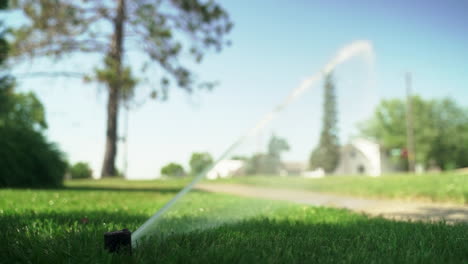 ground-level view of sprinkler forcefully watering park grass