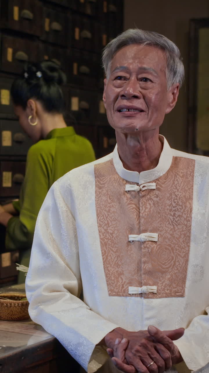Elderly Asian Herbalist Smiling at Camera at Pharmacy