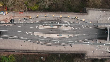 Top-down-aerial-shot-of-the-Clifton-suspension-bridge-road-below-with-passing-traffic-crossing-the-River-Avon,-Bristol,-during-overcast-cloudy-day