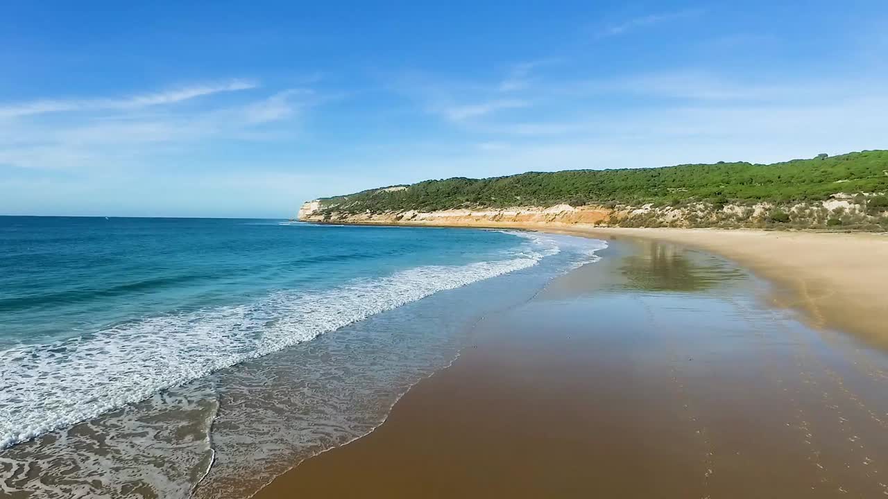 Vista aérea sobrevoando um casal exercitando cavalos na costa de Cádis.