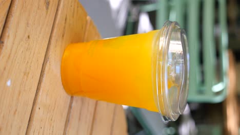 orange juice in a plastic cup on a wooden table