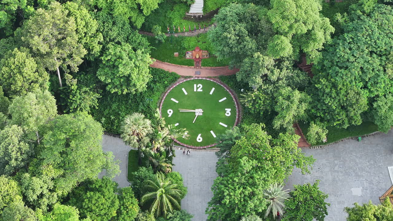 Aerial video of Phnom Penh’s Wat Phnom Park shows the iconic hilltop clock embedded in lush greenery, surrounded by shaded walking paths and tall trees
