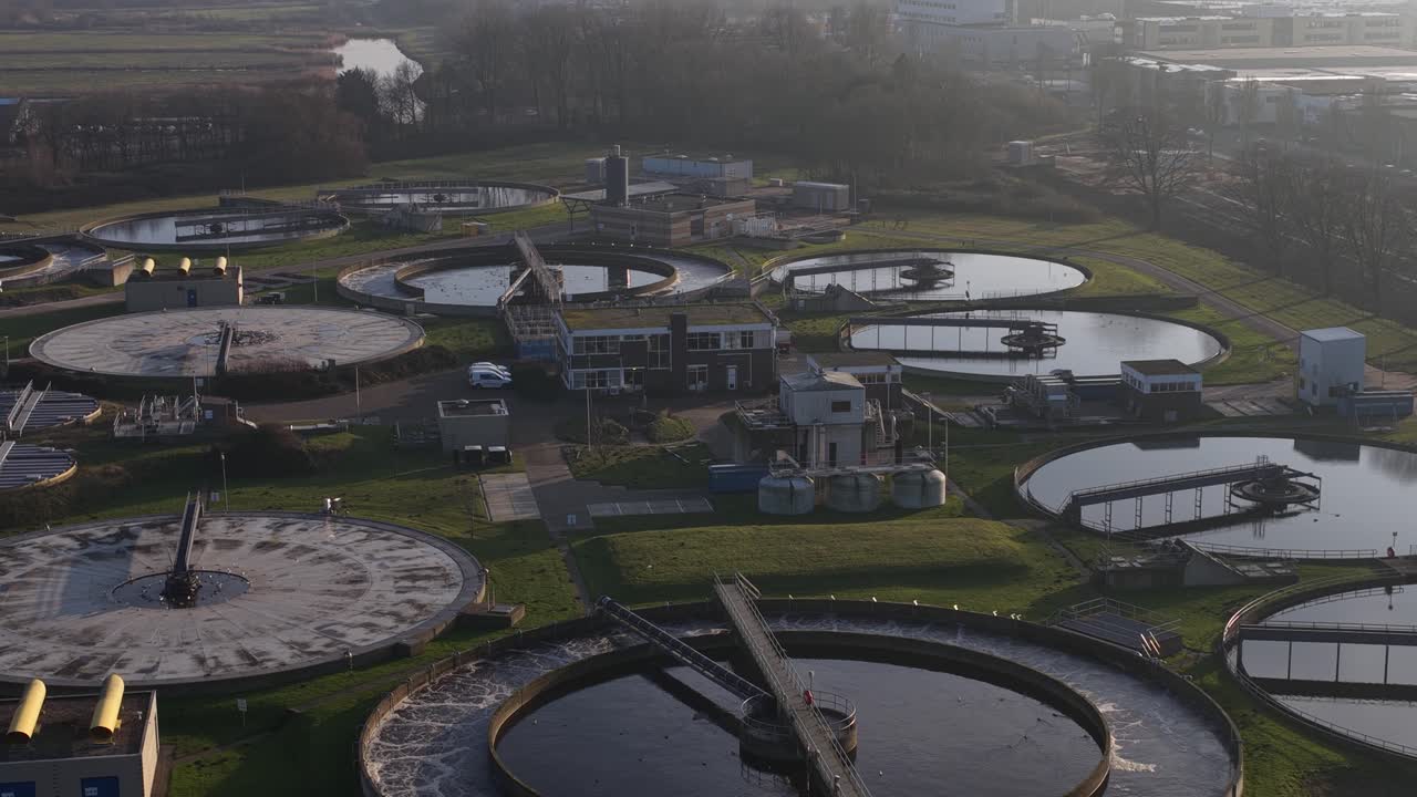 Aerial drone video of a wastewater and sewage treatment plant in Haarlem, Netherlands, showing water purification infrastructure, circular basins, environmental management, and urban sanitation system