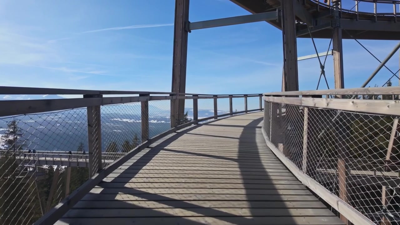 SkyWalk Serce Poronina observation deck near Male Ciche, Poland, with snowy Tatra mountain views, forested slopes, and elevated wooden and steel walkways on a sunny winter day.
