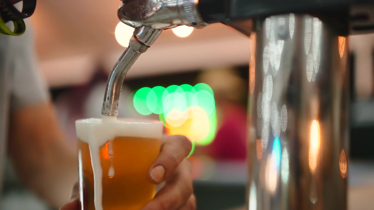 Barmen, taze fıçı birayı plastik bir bardağa dolduruyor.