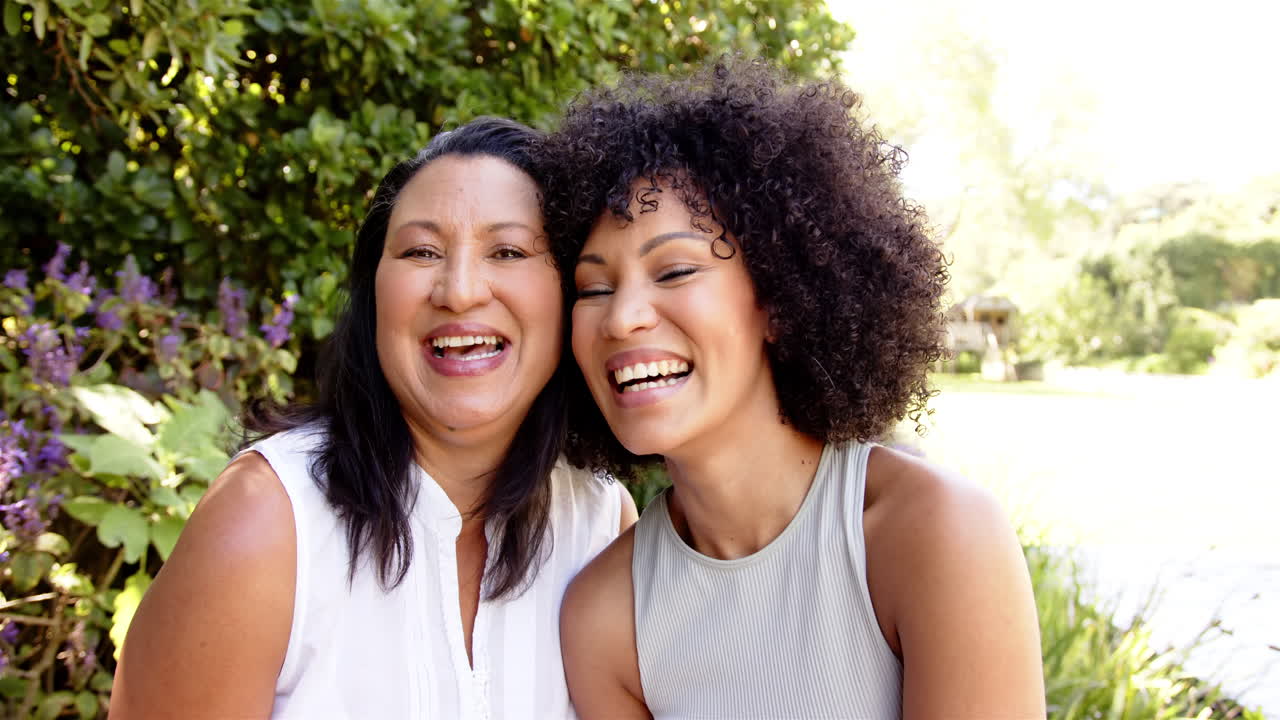 Smiling mother and adult daughter posing together outdoors, enjoying quality time in garden
