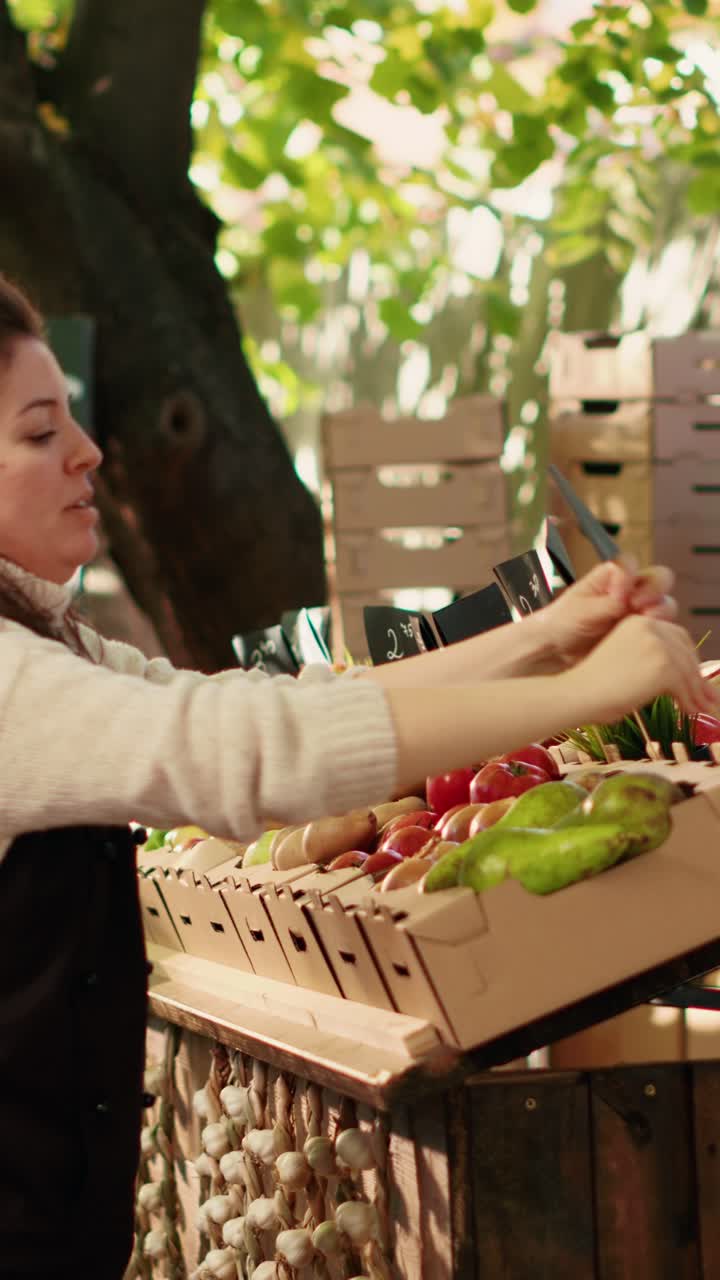 Video verticale: venditrice felice che applica i cartellini del prezzo sulle cassette di verdure al mercato agricolo