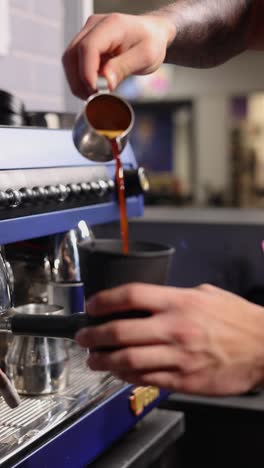 barista pouring coffee into a paper cup