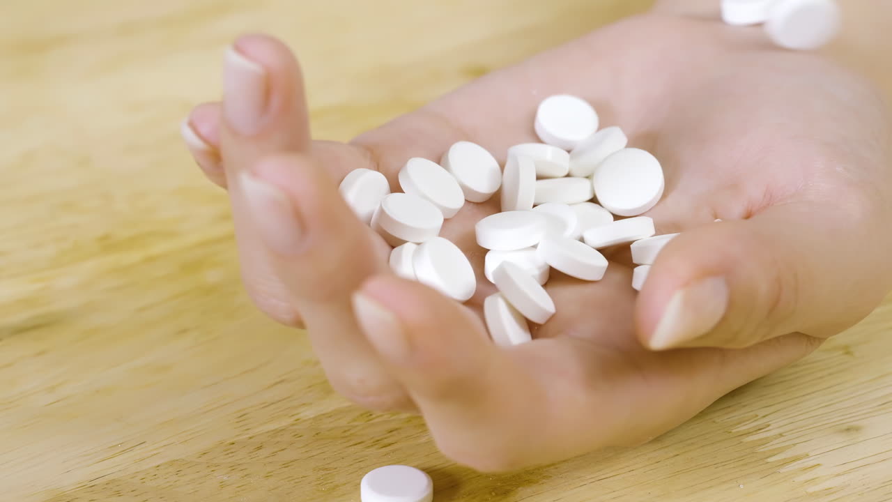 Close-up of a woman's hands pouring white pills from a medicine prescription bottle into an open hand, , representing health care, nutrition, and supplementation