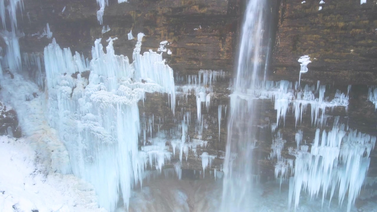 Drone em ascensão com inclinação para baixo pela Cachoeira Peričnik congelada, com imponentes pingentes de gelo e água corrente, Eslovênia.