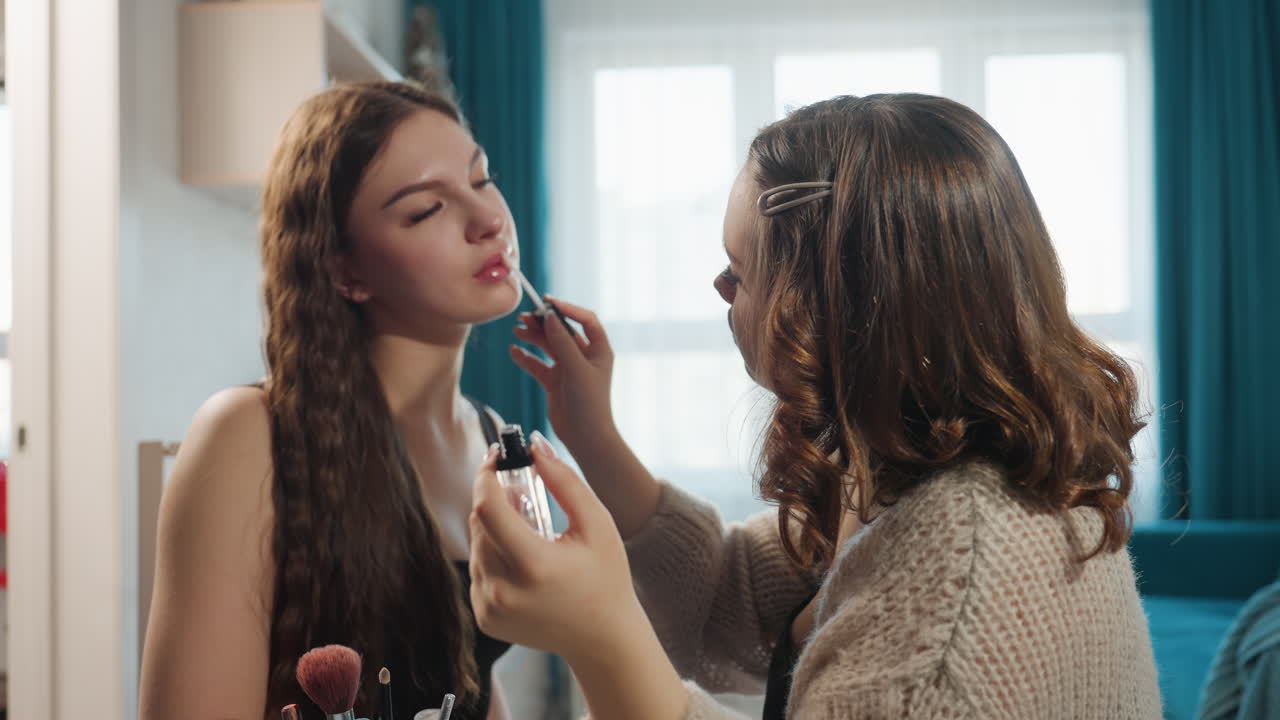 Caucasian Friends Sharing Makeup Lesson At Table, Daylight Through Window, Multiple Brushes And Palette On Glass Table, One Applying Lipstick While Other Holds Mirror, Focused Practice, Playful