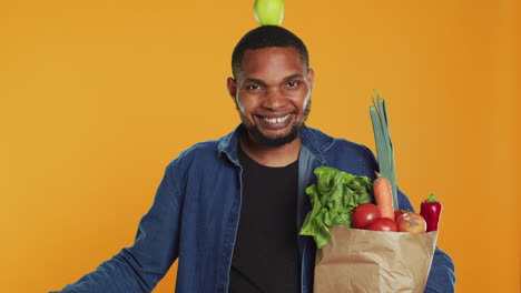 un tipo vegano lúdico bailando con una manzana colocada en su cabeza