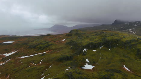 Aerial-view-of-snow-kissed-mountain-tops-with-overcast-skies-and-more-alps-in-the-distance