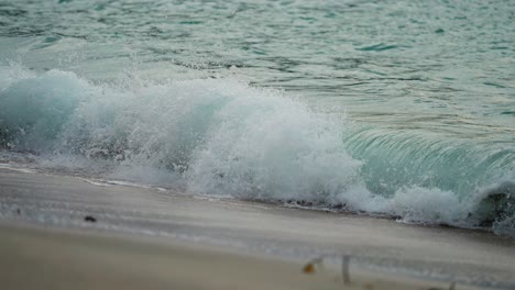 powerful waves are crashing and spilling on the sandy shore