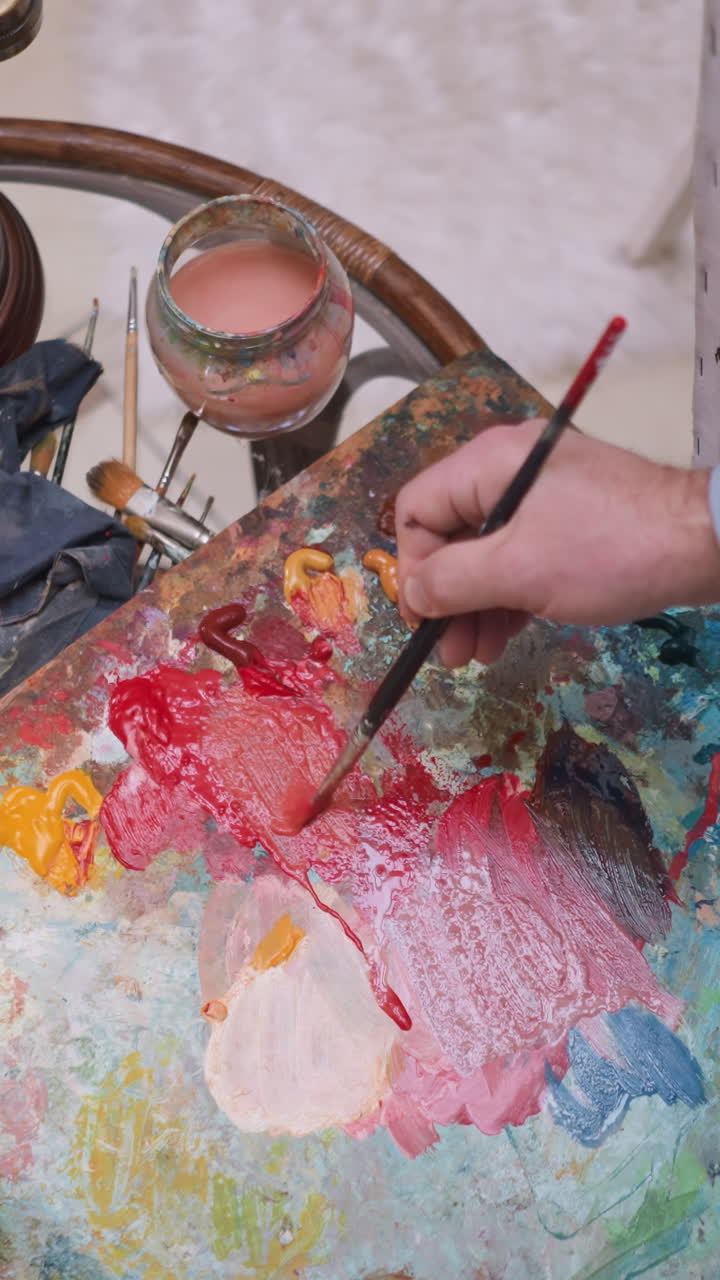 el hombre toma el color de la paleta con el pincel. el pintor demuestra la capacidad de mezclar sin problemas los colores y crear una paleta armoniosa para las pinturas