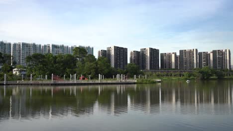 beautiful tranquil view of the lake with reflection of residential estate on the calm water and mrt train passing through in jurong lake gardens, singapore.