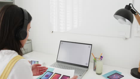 diseñadora biracial en el escritorio haciendo una llamada de video en la computadora portátil con espacio de copia en la pantalla, cámara lenta