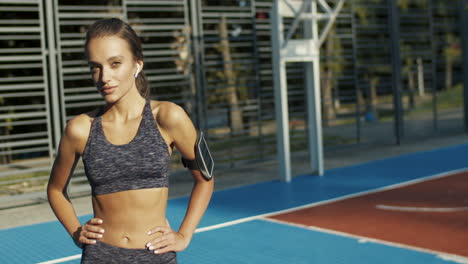 portrait shot of beautiful sexy slim woman in sporty outfit smiling joyfully to camera on sunny summer morning