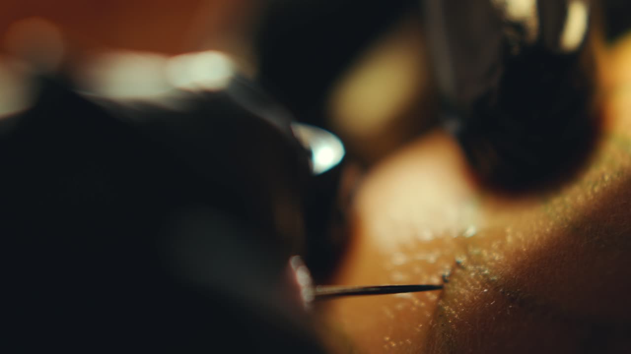 Mani di tatuatore che perforano la pelle con ago e applicano inchiostro